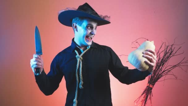 Jonge man in een zombie kostuum voor halloween, met pompoenen in zijn handen. 4k, slow-motion. Close-up — Stockvideo