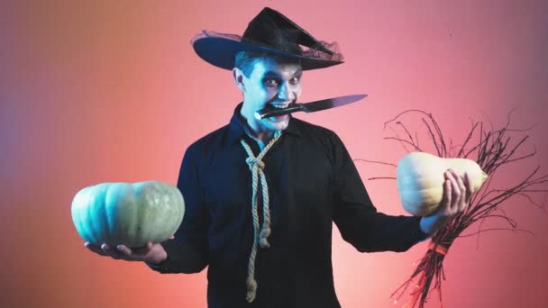junger Mann im Zombie-Kostüm zu Halloween, mit Kürbissen in den Händen. 4k, Zeitlupe. Nahaufnahme