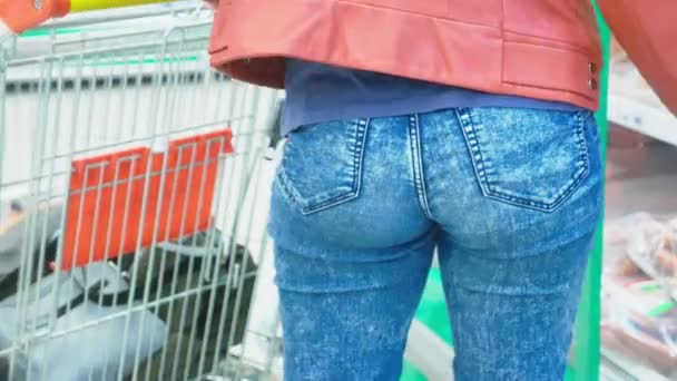 Una mujer en un supermercado está pasando por la canasta más allá de los mostradores. 4k, primer plano, una mujer camina por el supermercado . — Vídeo de stock