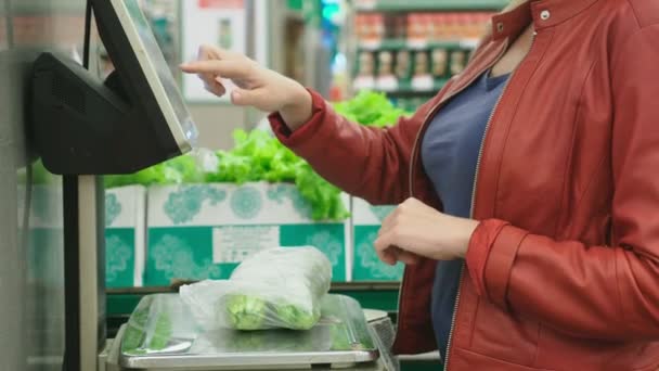 Een vrouw in een supermarkt kopen van groenten. komkommers en tomaten, met een gewicht op de weegschaal. zelfbediening. 4k — Stockvideo