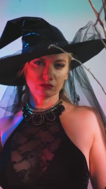 güzel genç seksi kadın kara cadı kostüm ve bir süpürge ile şapka içine belgili tanımlık fotoğraf makinesi ve gülümseyerek bakar. kopya alanı. 4k, ağır çekim