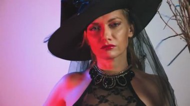güzel genç seksi kadın kara cadı kostüm ve bir süpürge ile şapka içine belgili tanımlık fotoğraf makinesi ve gülümseyerek bakar. kopya alanı. 4k, ağır çekim