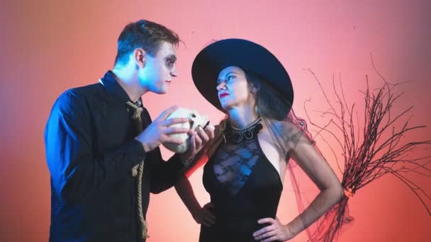 Красивая пара, мужчина и женщина в костюмах ведьмы и зомби на Хэллоуин, 4К, замедленная съемка, держат череп в руках. поздравления с праздником , — стоковое видео