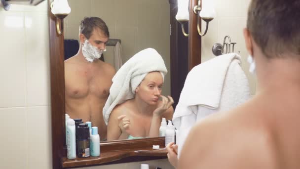 Vackert par, man och kvinna, tvätta tillsammans i badrummet framför spegeln. 4k, ultrarapid, de störa varandra stående framför spegeln — Stockvideo
