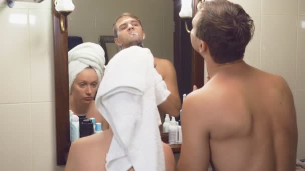美しいカップル、男と女は、鏡の前で浴室で一緒に洗ってください。4 k、スローモーション、女性がかかる彼女からかみそりの夫し、彼女の脇の下を剃る開始 — ストック動画