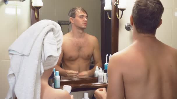 Belo casal, homem e mulher, lavar juntos no banheiro em frente ao espelho. 4K, câmera lenta, eles interferem uns com os outros em frente ao espelho — Vídeo de Stock