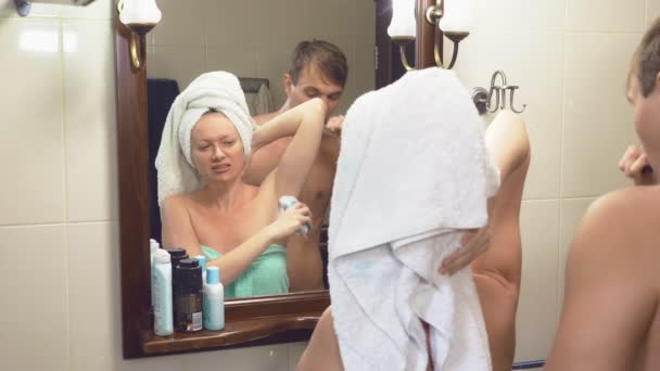 Vackert par, man och kvinna, tvätta tillsammans i badrummet framför spegeln. 4k, ultrarapid, de störa varandra stående framför spegeln — Stockvideo