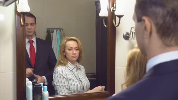 Супруги, муж и жена собираются в ванной перед зеркалом. чтобы их душили духами. 4k, slow motion — стоковое видео