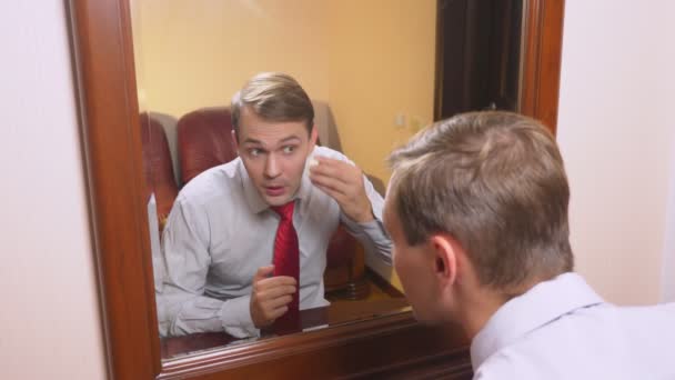 Le concept de métrosexualisme. un bel homme devant un miroir prend soin de son visage. fait le contour du visage, maquillage quotidien. 4k, au ralenti — Video