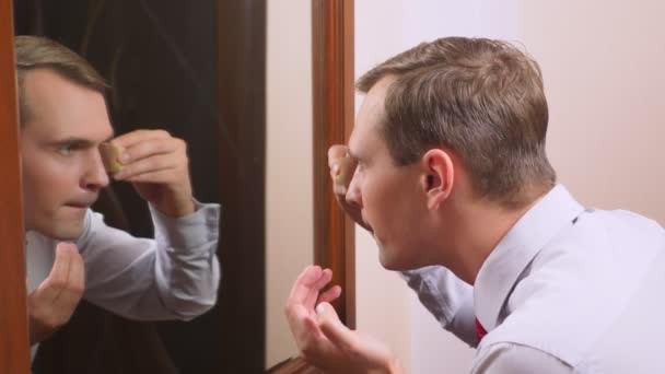 Понятие метросексуализма. красивый мужчина перед зеркалом заботится о своем лице. делает контур лица, повседневный макияж. 4k, slow motion — стоковое видео