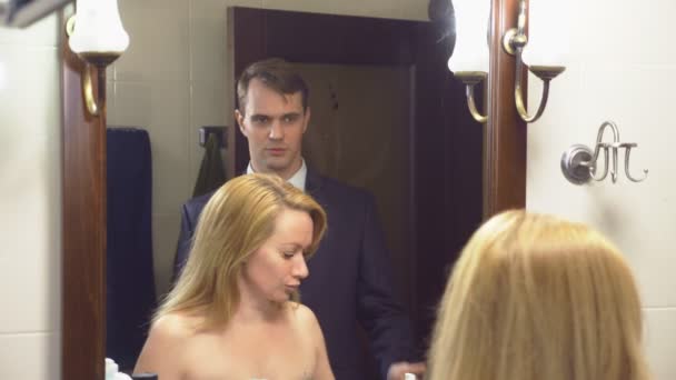 Пара, муж и жена собираются в ванной. Муж уже одет и ждет свою несобранную жену. 4k, slow motion — стоковое видео