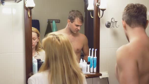 Hermosa pareja, hombre y mujer, lavar juntos en el baño delante del espejo. 4k, cámara lenta, un hombre se afeita . — Vídeos de Stock