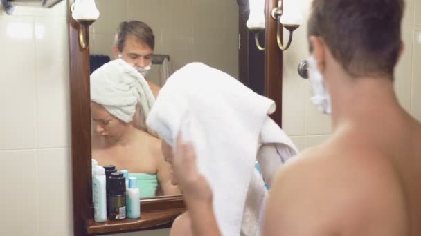 Vackert par, man och kvinna, tvätta tillsammans i badrummet framför spegeln. 4k, ultrarapid, de störa varandra — Stockvideo