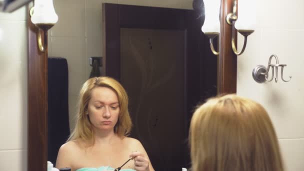 4 k. αργή κίνηση. Μια γυναίκα χρωματίζει τις βλεφαρίδες της μπροστά από έναν καθρέφτη στο μπάνιο — Αρχείο Βίντεο