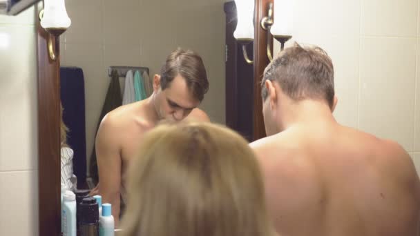 Пара, муж и жена собираются в ванной. уже одетая жена ждет своего мужа, который еще не собрался. 4k, slow motion — стоковое видео