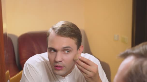 Le concept de métrosexualisme. un bel homme devant un miroir prend soin de son visage. fait le contour du visage, maquillage quotidien. 4k, au ralenti — Video