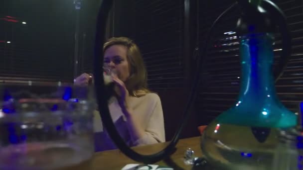 Una chica fuma una cachimba y bebe cerveza en un club nocturno — Vídeo de stock