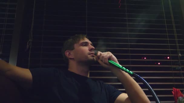 Хлопець курить кальян і п'є пиво в нічному клубі . — стокове відео