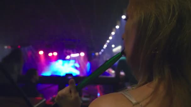 Uma menina fuma um narguilé e bebe cerveja em uma boate — Vídeo de Stock