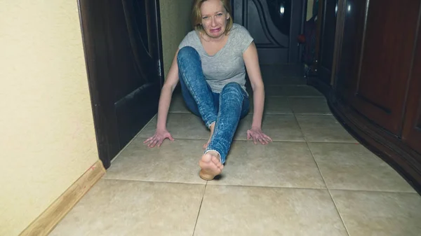 Horror, una chica se arrastra lejos de su investigador, cayendo al suelo en el pasillo de su casa . —  Fotos de Stock
