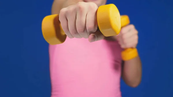 A man in a pink T-shirt with a deep neckline is boxing dumbbells. focus on dumbbells, body blurry. copy space — Stock Photo, Image