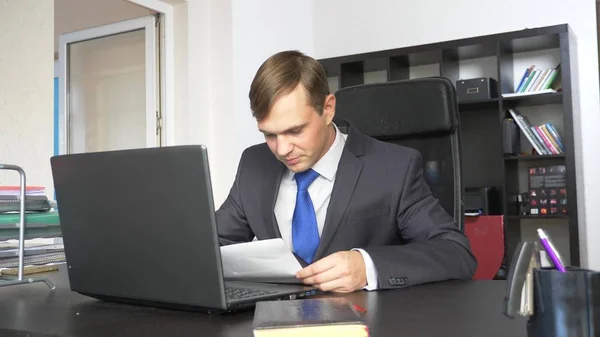 Человек изучает бумажный документ. Сидя в офисе — стоковое фото