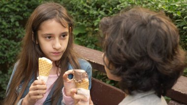 sevimli gençler, oğlan ve kız parkta dondurma yemek ve konuşmak