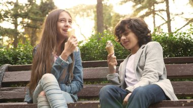sevimli gençler, oğlan ve kız parkta dondurma yemek ve konuşmak