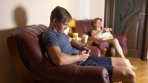 Una pareja de casados sentados en una silla y viendo televisión en casa juntos, tarde por la noche, oscuro . —  Fotos de Stock