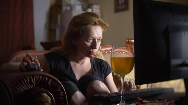 Femme avec ordinateur, boire de la bière à la maison dans le noir . — Photo