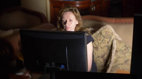 Mujer con computadora, bebiendo cerveza en casa en la oscuridad . — Foto de Stock