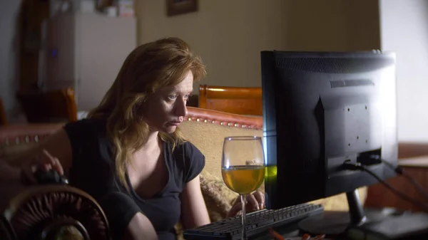 Mujer con computadora, bebiendo cerveza en casa en la oscuridad . — Foto de Stock