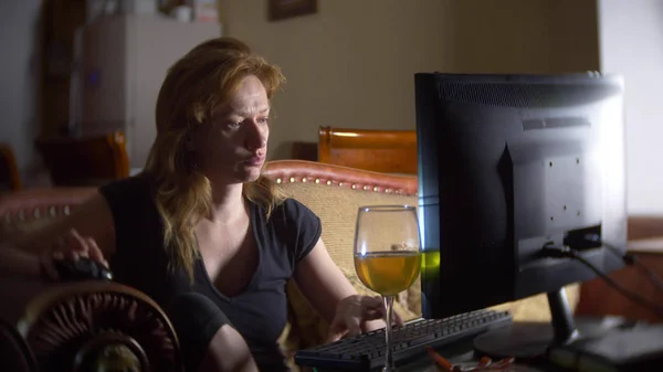 Mujer con computadora, bebiendo cerveza en casa en la oscuridad . — Foto de Stock