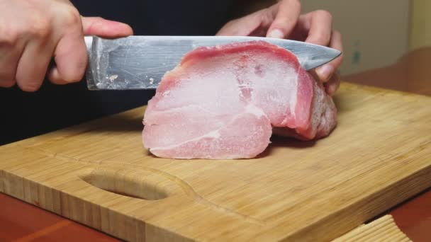 Ο άνθρωπος κόβει ωμά κατεψυγμένα κρέατα με ένα μαχαίρι σε αργή κίνηση. 4 k γκρο πλαν — Αρχείο Βίντεο