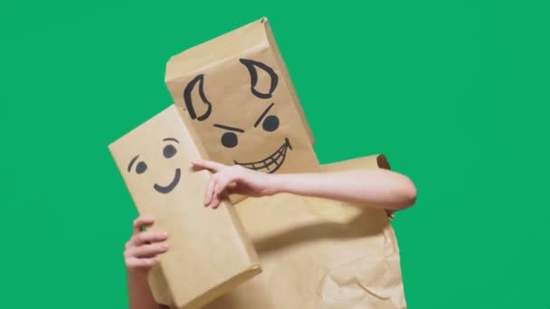 Concepto de emociones, gestos. un hombre con un paquete en la cabeza, con un emoticono pintado diablo, astuto, regodeándose. juega con el niño dibujado en la caja. engaño infantil, ingenuidad — Vídeo de stock