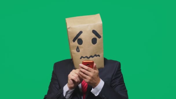 Concetto di emozione, gesti. un uomo con un pacco in testa, con un sorriso dipinto che piange, triste, che parla al telefono — Video Stock