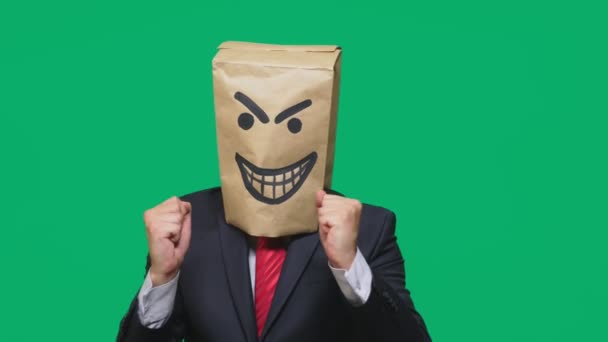 Concept of emotion, gestures. a man with a package on his head, with a painted smiley angry, sly, gloating — Stock Video