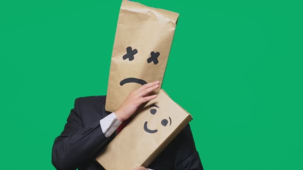 Concepto de emociones, gestos. un hombre con un paquete en la cabeza, con un emoticono pintado, cansado, somnoliento. juega con el niño pintado en la caja . — Vídeos de Stock