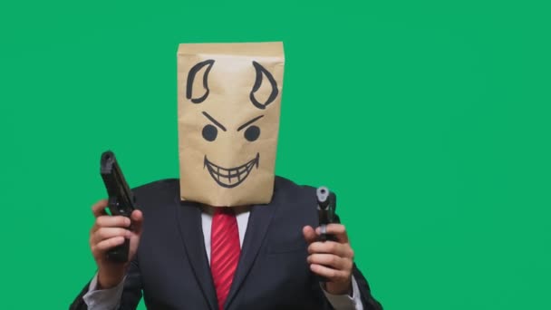 Konzept der Emotion, Gesten. ein Mann mit einem Paket auf dem Kopf, mit einem aufgemalten Smiley wütend, listig, schwärmerisch, Teufel, Pistolen in der Hand — Stockvideo