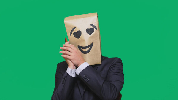 concept of emotions, gestures. a man with paper bags on his head, with a painted emoticon, smile, joy, love eyes.