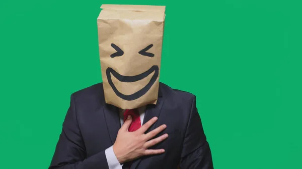 Concepto de emociones, gestos. un hombre con bolsas de papel en la cabeza, con un emoticono pintado, sonrisa, alegría — Foto de Stock