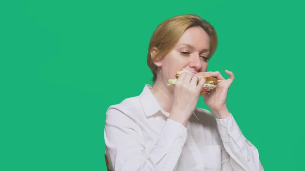 Geschäftsfrau beim Sandwich auf grünem Hintergrund. Konzept für schnelles Mittagessen. — Stockfoto
