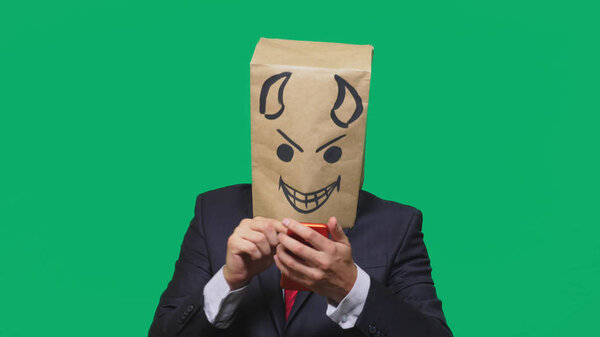concept of emotions, gestures. a man with a package on his head, with a painted black smiley face, a devil, crafty, gloating, talking on a mobile phone