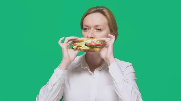 Geschäftsfrau beim Sandwich auf grünem Hintergrund. Konzept für schnelles Mittagessen. — Stockfoto