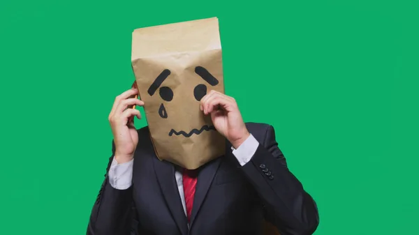 Conceptul de emoție, gesturi. un om cu un pachet pe cap, cu un zâmbet pictat plângând, trist, vorbind la telefon — Fotografie, imagine de stoc