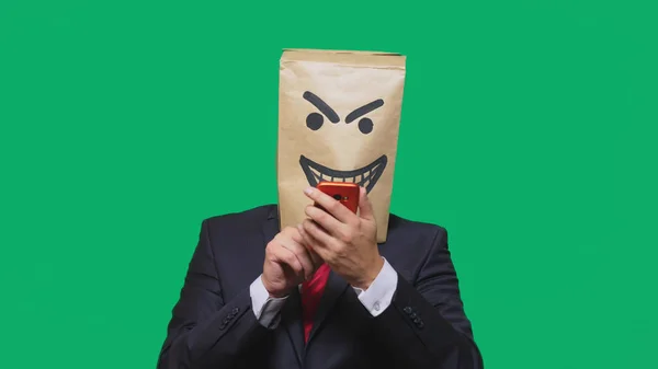 Conceptul de emoții, gesturi. un om cu un pachet pe cap, cu un emoticon negru pictat, viclean, gloating, vorbind pe un telefon mobil . — Fotografie, imagine de stoc