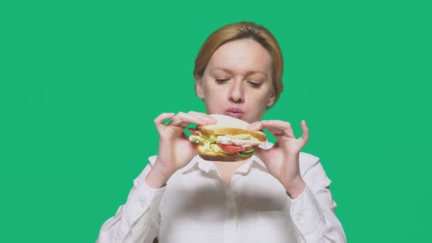 Affärskvinna som äter en smörgås på en grön bakgrund. snabb lunch koncept. — Stockvideo