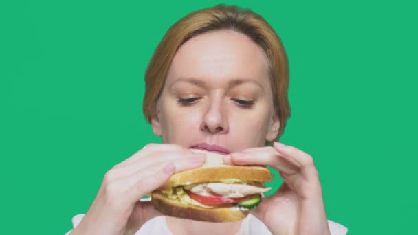 Mujer de negocios comiendo un sándwich sobre un fondo verde. concepto de almuerzo rápido . — Vídeo de stock