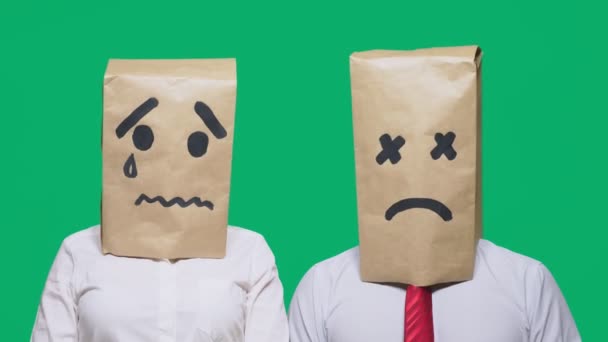 Concepto de emociones, gestos. un par de personas con bolsas en la cabeza, con un emoticono pintado, triste, llorando, cansado — Vídeo de stock