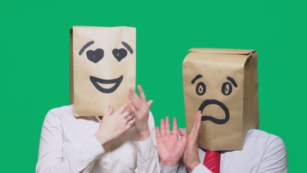 Concepto de emociones, gestos. un par de personas con bolsas en la cabeza, con un emoticono pintado, una sonrisa, ojos enamorados, y el segundo con una máscara de miedo, miedo. concepto de acoso sexual — Vídeos de Stock